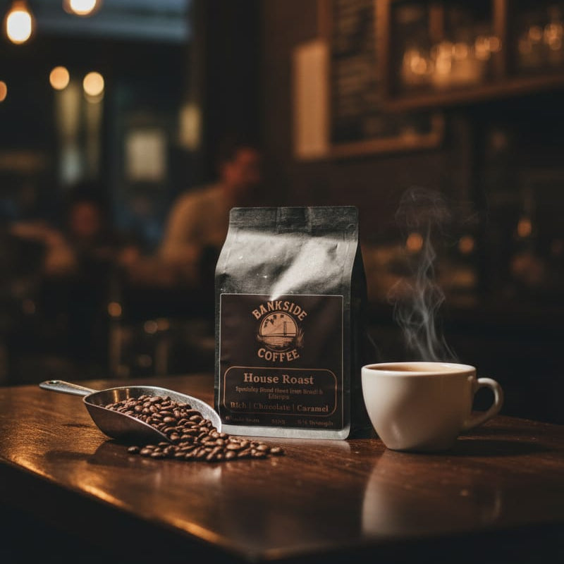 Steaming coffee cup and coffee beans with a coffee bag on a wooden table in a dimly lit cafe.